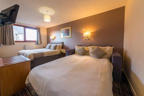 a hotel room with two beds and a tv at Castletown Hotel in Castletown