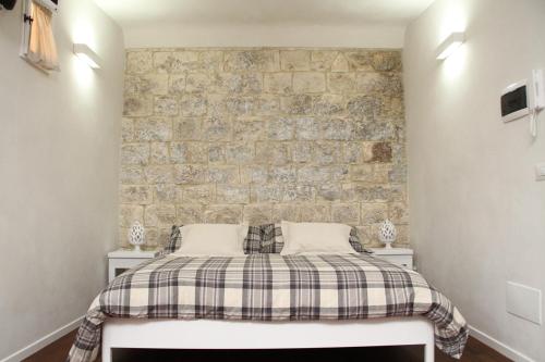 a bed in a room with a brick wall at Alla Corte del Conte in Conversano