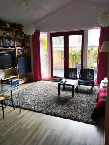een woonkamer met een bank, stoelen en een tafel bij B&B 16C Maassluis NL in Maassluis