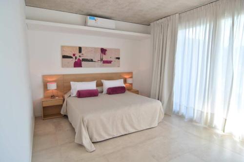 a white bedroom with a large bed and a window at Open Pinamar Resort in Pinamar
