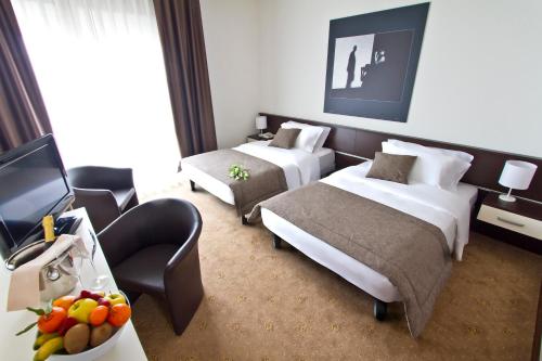 una camera d'albergo con due letti e una televisione di Hotel Eurorest a Conegliano