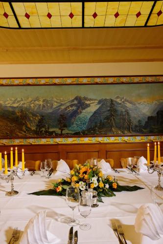 a table in a restaurant with a painting on the wall at Hotel Ambassador in Brig