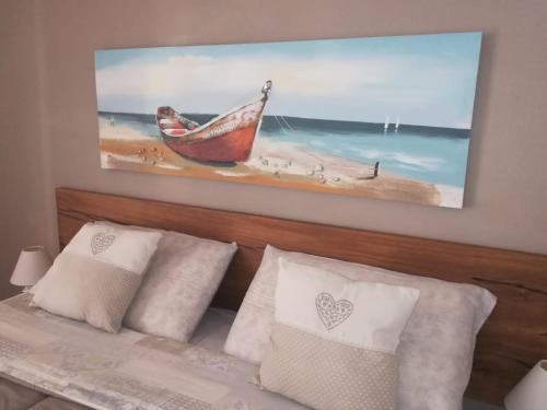 a painting of a boat on a beach next to a bed at Etesia in Olbia