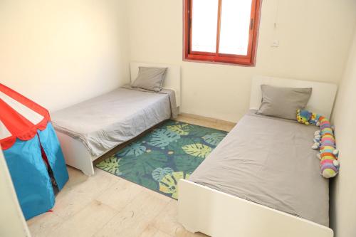 a bedroom with two beds and a rug at valentine House in Deir Ḥannā