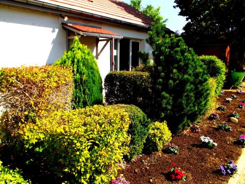 a garden with bushes and flowers in front of a house at Premiere Classe Chantilly Sud Luzarches in Chaumontel