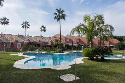 una piscina en un patio con palmeras en Apartamento Pink Mariposas en Chiclana de la Frontera