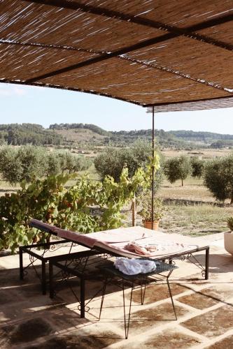 a patio with a table and a bench with a view at Agroturisme Gossalba in Sant Joan