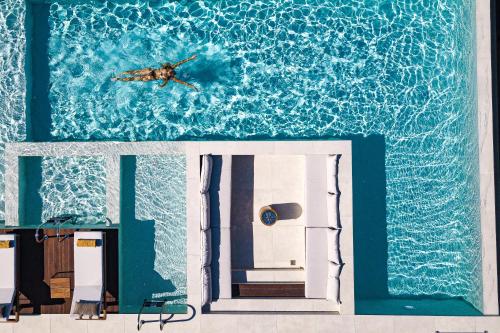 eine Person, die in einem Haus im Wasser schwimmt in der Unterkunft Zillion Villa, intangible beachfront luxury, By ThinkVilla in Panormos
