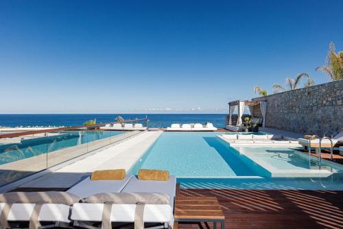 uma piscina com cadeiras e o oceano ao fundo em Zillion Villa, intangible beachfront luxury, By ThinkVilla em Panormos - Rethymno