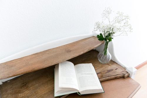 ein Buch und eine Vase Blumen auf dem Tisch in der Unterkunft Vázquez de Mella Gran Vía in Madrid