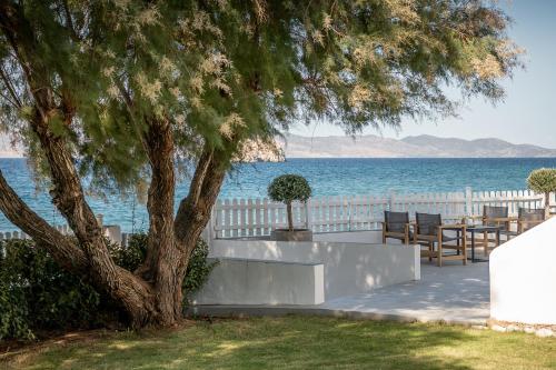 a tree sitting next to a white fence and the ocean at Four Seasons Hydra Luxury Suites in Hydra