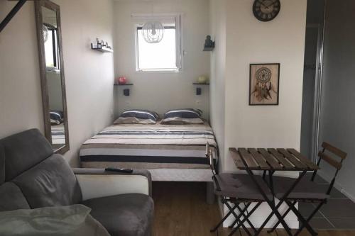 een kleine slaapkamer met een bed en een bank bij Studio récent tout équipé in Villenave-dʼOrnon