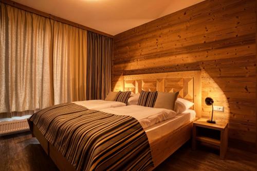 a bedroom with a large bed with a wooden wall at DaSus Lux&Wellness Apartments Sosana in Belá