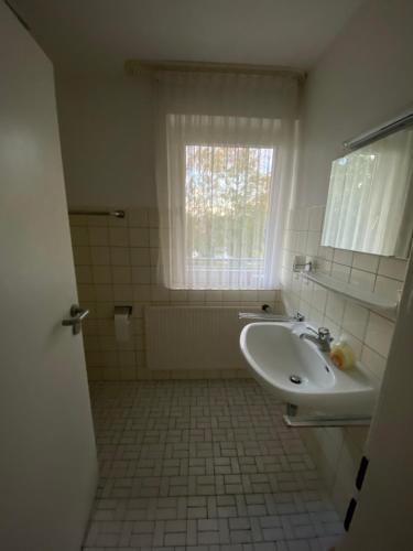 a white bathroom with a sink and a window at Hotel Seehaus in Horn-Bad Meinberg