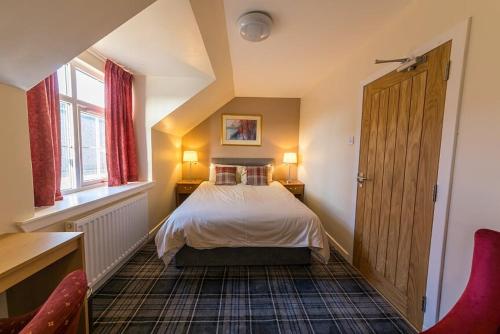 a bedroom with a bed and a desk and a window at Castletown Hotel in Castletown
