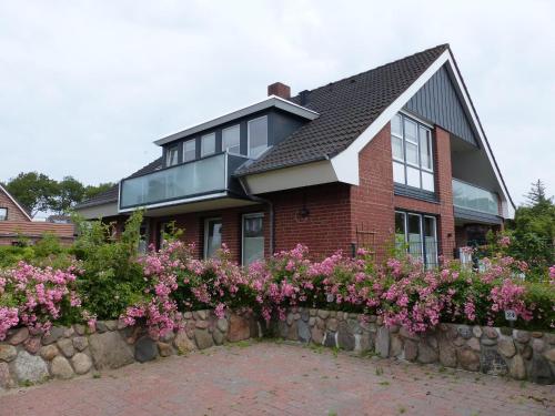 a brick house with flowers on a stone wall at Captain Baack in Nieblum