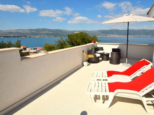 a balcony with red and white chairs and an umbrella at Apartment Anđa-3 by Interhome in Trogir
