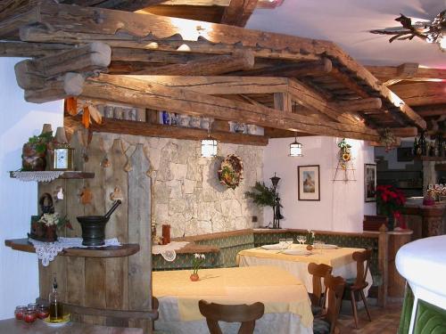 a restaurant with two tables and a stone wall at Hotel Garni Soreie in Pozza di Fassa