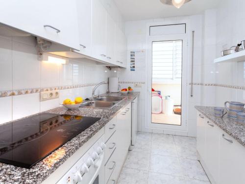 a white kitchen with white cabinets and a sink at Apartment L'Olivar II by Interhome in Llança