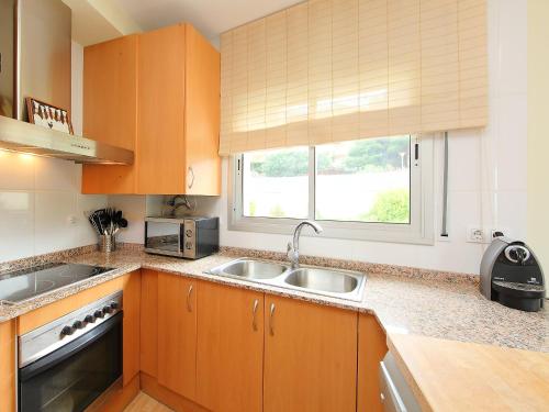 d'une cuisine avec des placards en bois, un évier et une fenêtre. dans l'établissement Apartment Fane De Baix II by Interhome, à Llançà