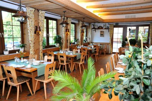 un restaurante con mesas de madera, sillas y plantas en Landgasthof Adler Pelzmühle en Biederbach Baden-Württemberg