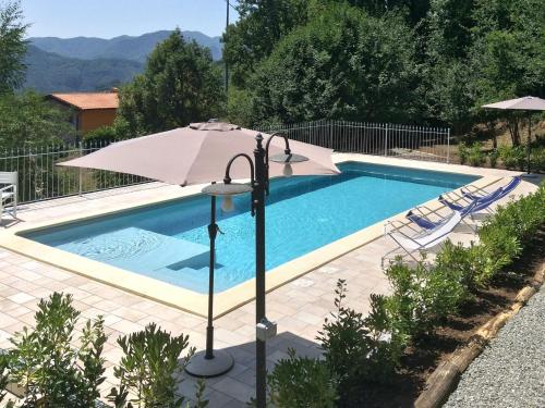 a swimming pool with an umbrella and chairs at Holiday Home Del Regolo by Interhome in Molazzana