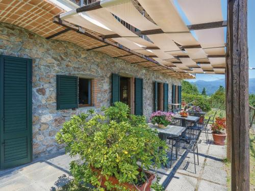 a patio with tables and chairs and a stone building at Holiday Home Del Regolo by Interhome in Molazzana