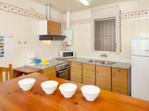 una cocina con una mesa de madera con cuatro tazones blancos. en Apartment La Rectoria by Interhome, en La Vall de Santa Creu