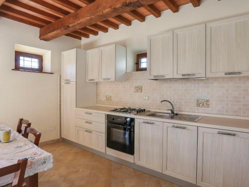 Una cocina con gabinetes blancos y un fregadero y una mesa. en Apartment Altana - CNG176 by Interhome, en Magnano