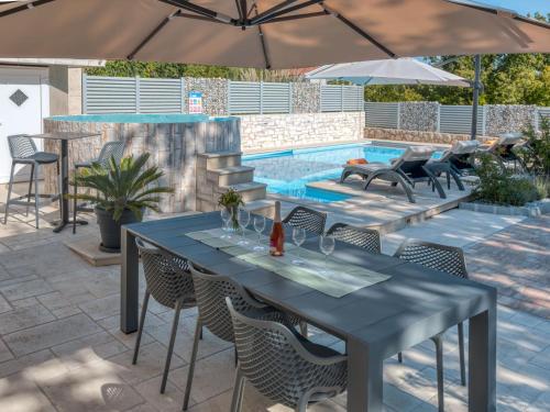 een patio met een tafel en stoelen en een zwembad bij Holiday Home Lavendel - MLK159 by Interhome in Dobrinj