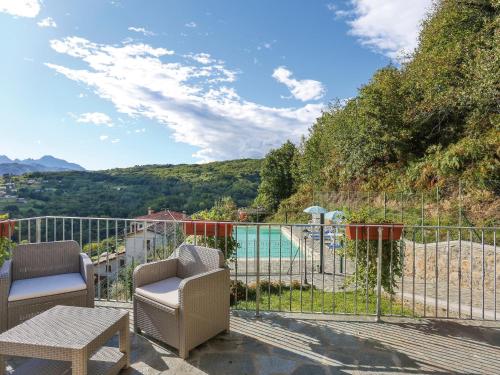 a balcony with two chairs and a view of a pool at Apartment Caminetto - CNG177 by Interhome in Magnano
