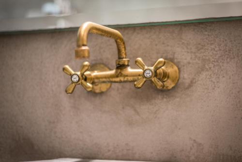a gold faucet on the wall of a bathroom at Thalassitra Private Pool Suites in Adamas