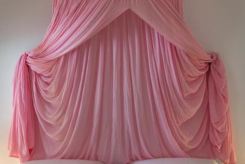 a pink curtain is hanging on a bed at Thalassitra Private Pool Suites in Adamas