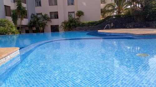 a large blue swimming pool in front of a building at Garden's Apartment in Funchal