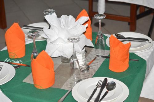 Royal Green Gardens Resort في ناكورو: طاولة عليها أطباق بيضاء ومناديل وأكواب برتقالية