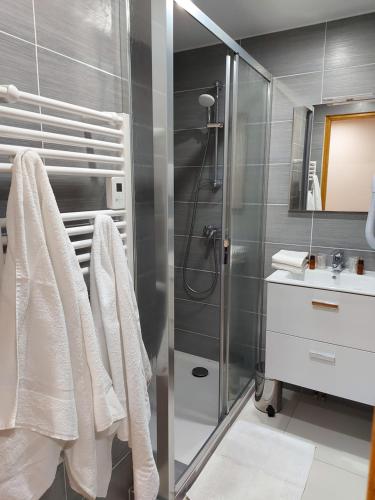 a bathroom with a shower with white towels and a sink at Hôtel La Montagne Fleurie in Barèges