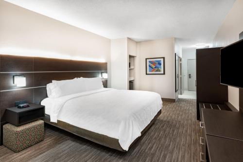 a hotel room with a bed and a flat screen tv at Holiday Inn Express Hotel & Suites Albuquerque - North Balloon Fiesta Park by IHG in Albuquerque