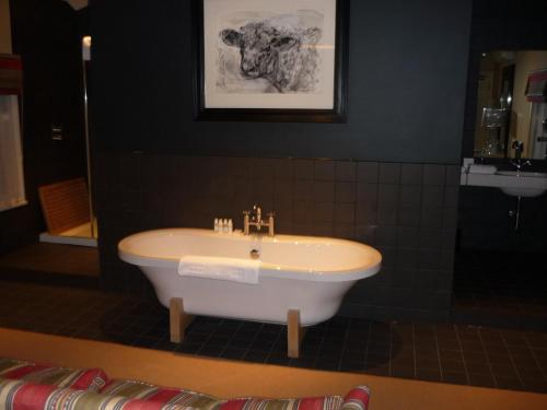 a bath tub in a bathroom with a sink at Milsoms Kesgrave Hall in Ipswich