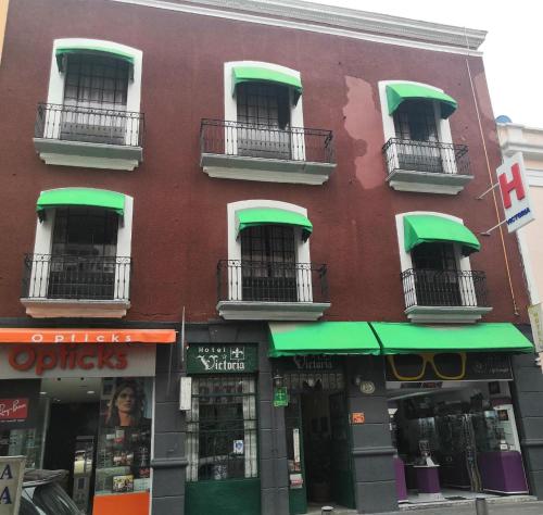 a building with green awnings and windows on a street at Hotel Victoria in Puebla