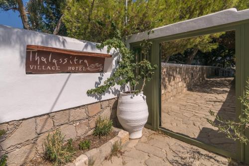 a large white vase with a plant in it next to a sign at Thalassitra Private Pool Suites in Adamas