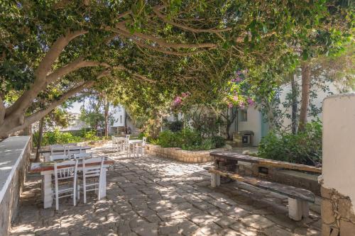 a group of tables and chairs under a tree at Thalassitra Private Pool Suites in Adamas