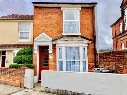 a red brick house with a red door at Purple Cloud Cosy 4 bed Cottage with Garden Parking Pet-Friendly in Portsmouth
