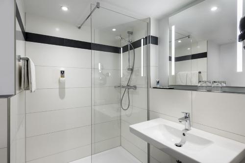 een witte badkamer met een douche en een wastafel bij Tools Hotel Laichingen in Laichingen