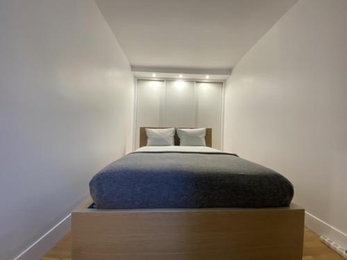 ein Schlafzimmer mit einem Bett mit einer blauen Decke in der Unterkunft Montparnasse Cozy Flat in Paris
