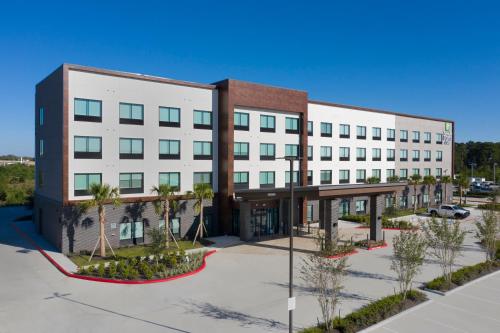 an image of a large white building with a parking lot at Holiday Inn Express & Suites Spring - Woodlands Area by IHG in Spring