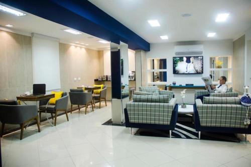 a lobby with chairs and tables and a person reading at Millian Hotel in Jundiaí