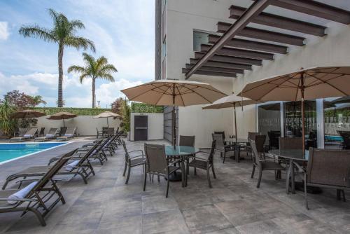 a patio with tables and chairs and umbrellas next to a pool at Holiday Inn Express and Suites Celaya by IHG in Celaya
