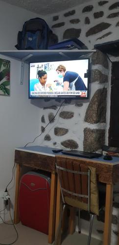 uma televisão na parede com uma mesa e uma cadeira em Branca Gonçalves Belmonte em Belmonte