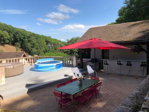 d'une terrasse avec une table et un parasol rouge. dans l'établissement Domaine Du Bas De Chene, à Saint-Sernin-du-Bois