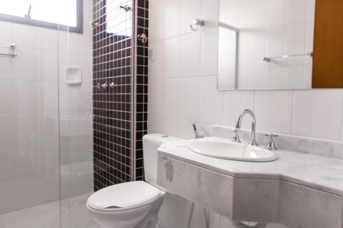 a white bathroom with a toilet and a sink at Hotel Maruá in São José dos Campos